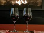 Two glasses of red wine in front of the fireplace