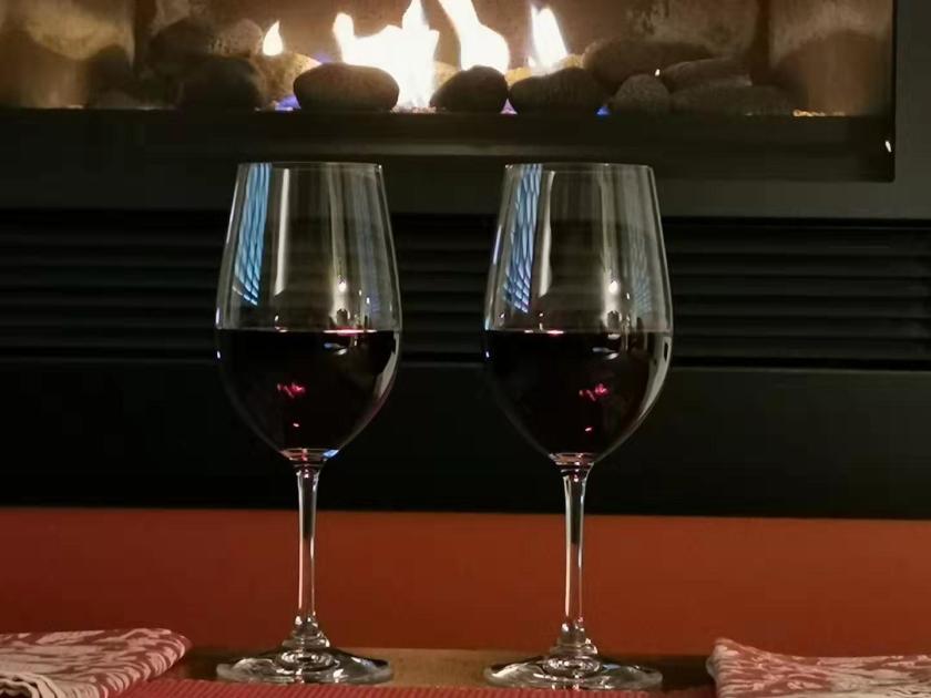 Two glasses of red wine in front of the fireplace